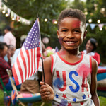A child with a U.S. flag and colorful face paint at a festive outdoor celebration.