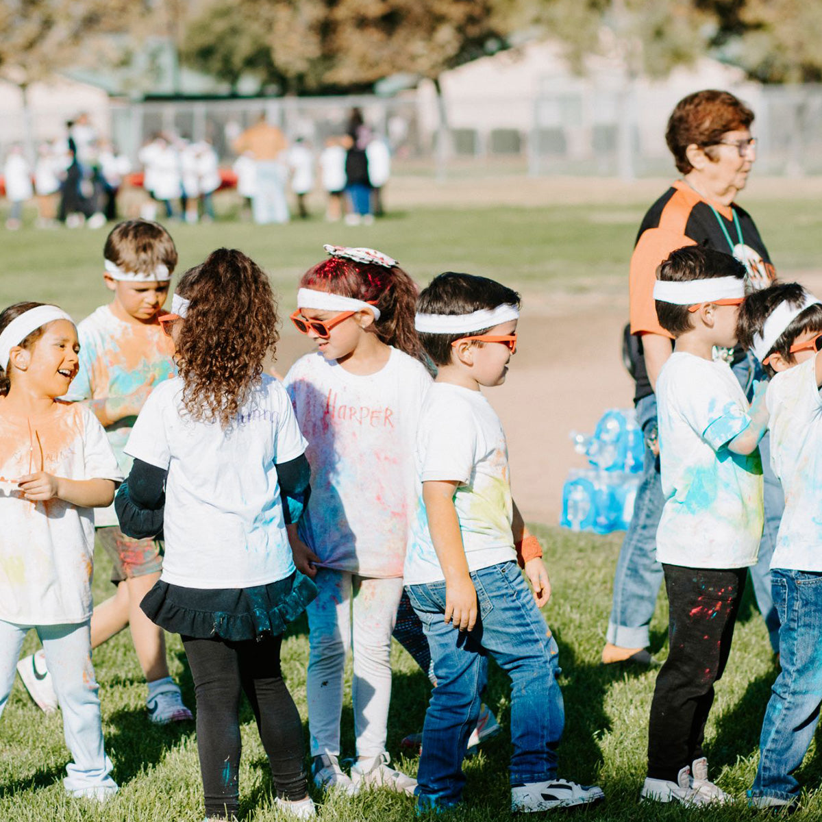Children participating in a color run event on a grassy field.